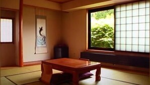 A traditional Japanese room with tatami flooring, a low wooden table, and a sliding shoji screen door. - Guesthouse Sakuya (Fujikawaguchiko)