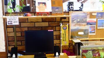 A reception desk with a computer monitor, a potted plant, and a fish tank.