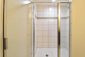 A walk-in shower with a tiled floor and a glass door. - Tile floors, spacious beachfront condo w/private balcony! (Destin)