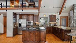 A spacious kitchen with wooden cabinets, a large island, and a stone accent wall.