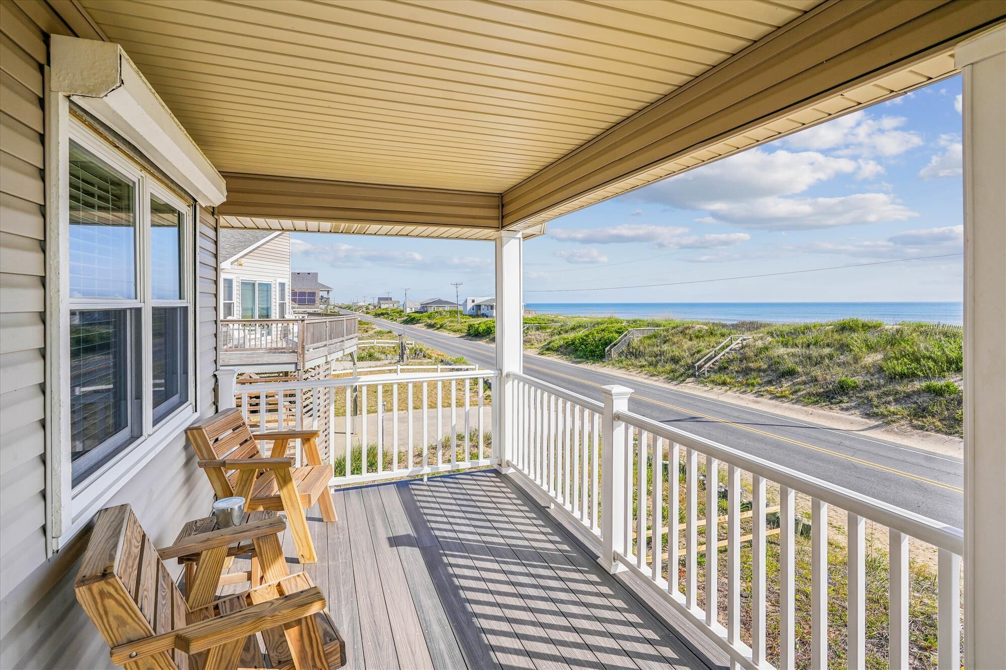 Une terrasse en bois avec une rambarde donnant sur une route et une plage.