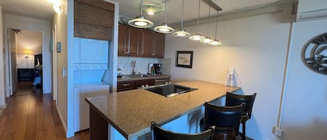A modern kitchen with granite countertops, stainless steel appliances, and pendant lighting.