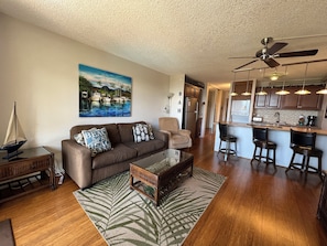 A living room with a sofa, coffee table, and a painting of a beach scene.