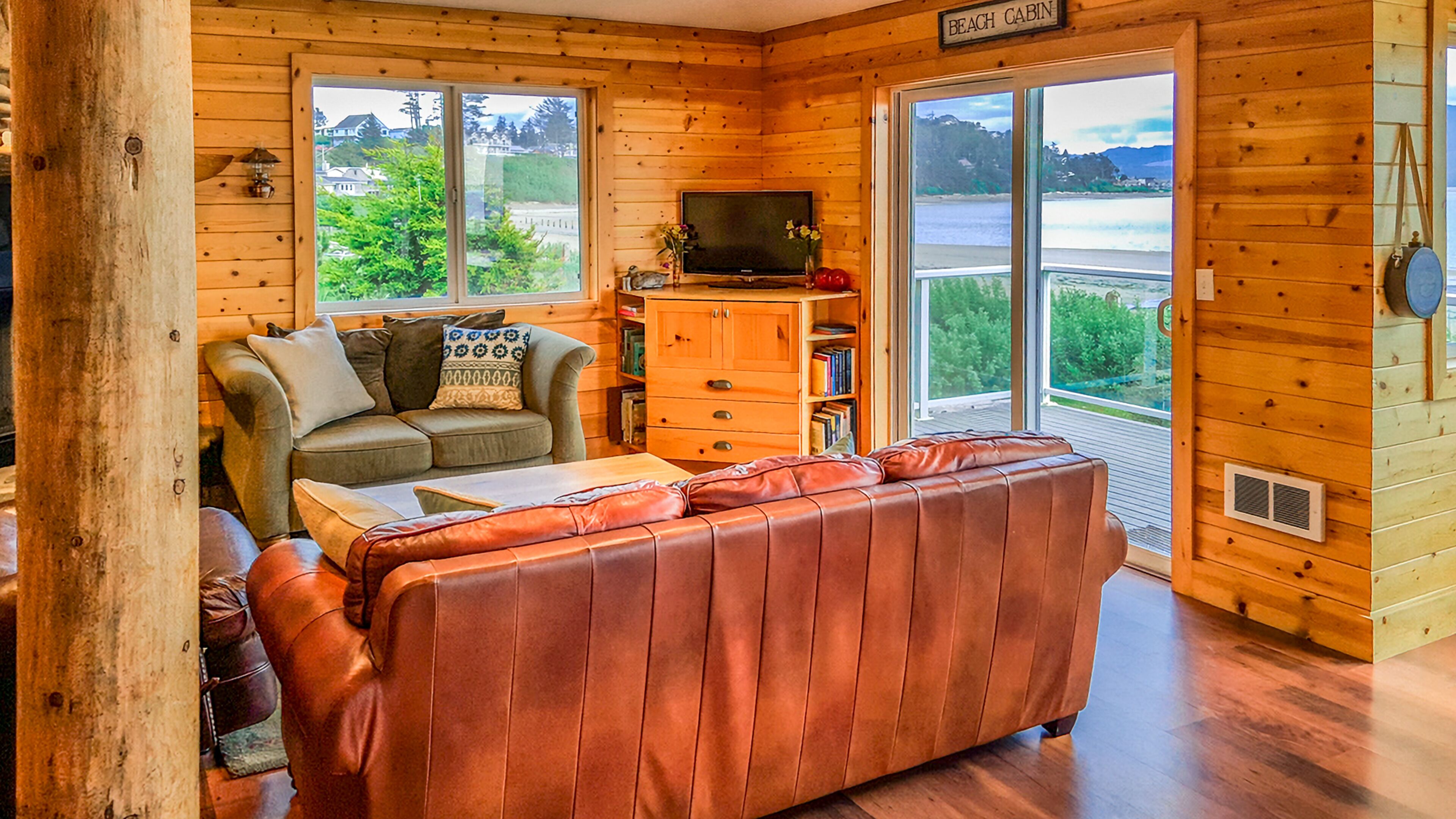 A cabin interior with a sofa, a television, and a view of the outdoors.