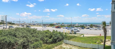 Un parking rempli de voitures, une plage et un ciel dégagé.