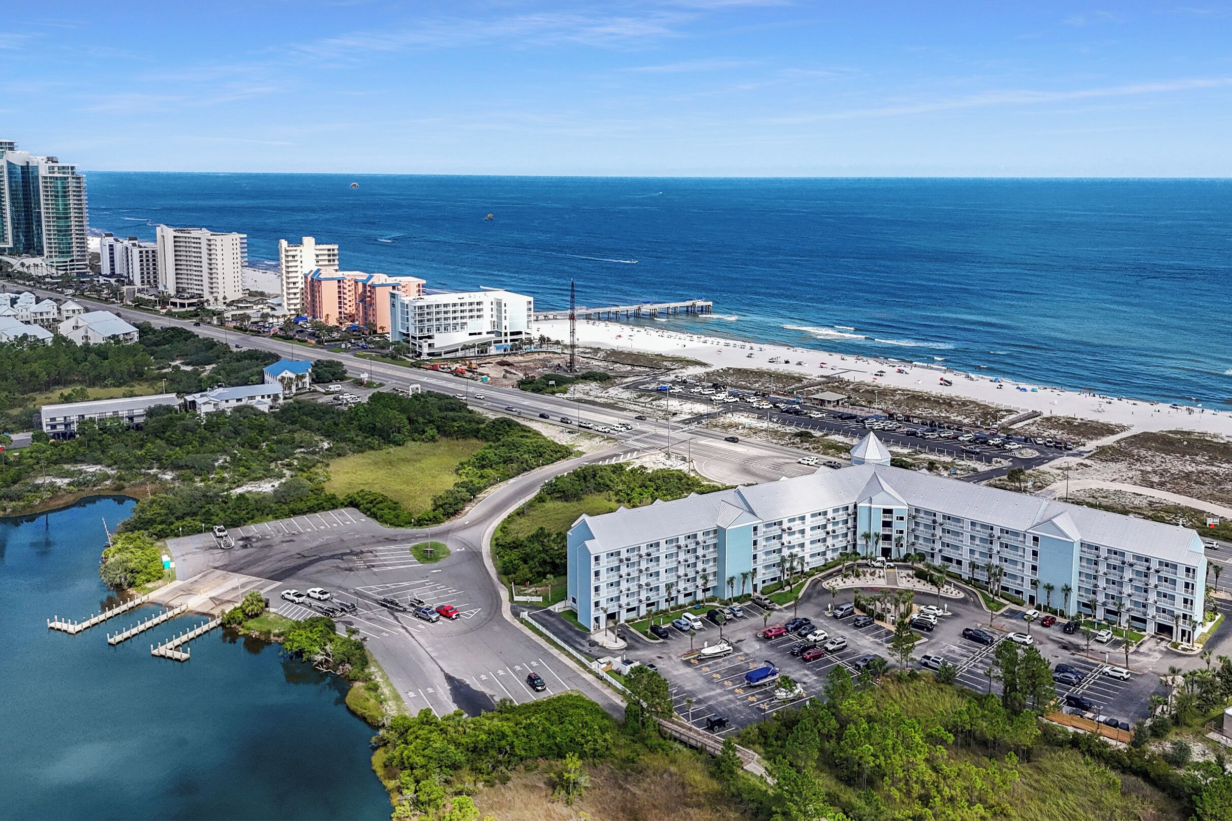 A coastal hotel with a parking lot, a beach, and a pier.
