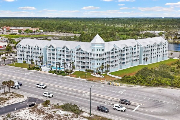 A large hotel with multiple balconies, a central tower, and a waterfront view.