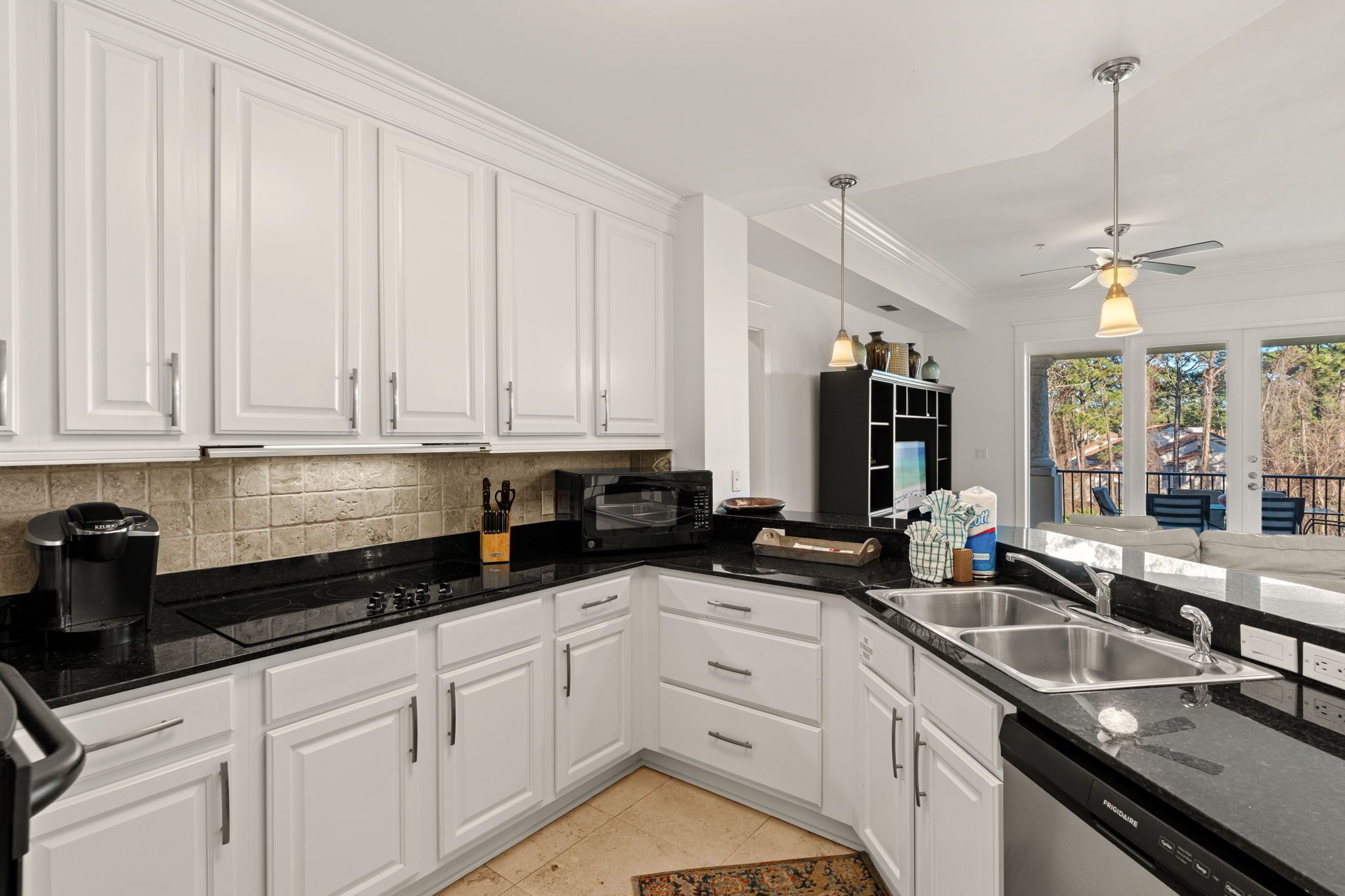 A modern kitchen with white cabinets, a black countertop, a built-in microwave, and a sink.