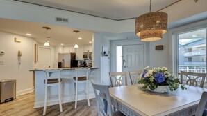 Une cuisine moderne avec des meubles blancs, un îlot central et des luminaires suspendus.