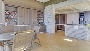 A modern kitchen with built-in cabinets, a dining area with a table and chairs, and a kitchen island with a sign indicating social distancing measures.