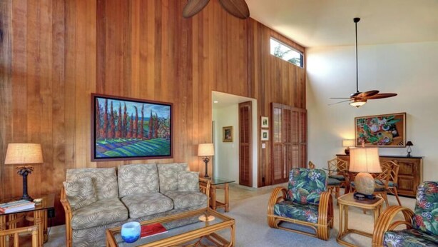 A living room with a wooden wall, a sofa, a coffee table, and a painting.