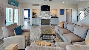 A spacious living room with a sofa, coffee table, and a fireplace. - Front Row | Pet-Friendly, Stunning Beach Views (Galveston)