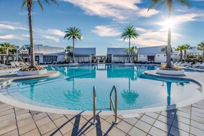 A pool area with two separate pools, palm trees, and lounge chairs.