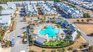 An aerial view of a resort with multiple buildings, a central swimming pool, and surrounding palm trees. - "Lucky Old Sun" - Prominence - 3BR / 2.5 BA - Sleeps 9 - 6 Passenger Golf Cart (Santa Rosa Beach)