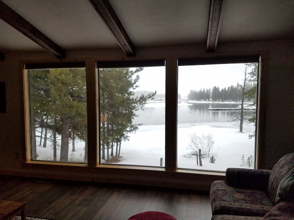 Une pièce dotée d’une grande fenêtre donnant sur un lac et des arbres.