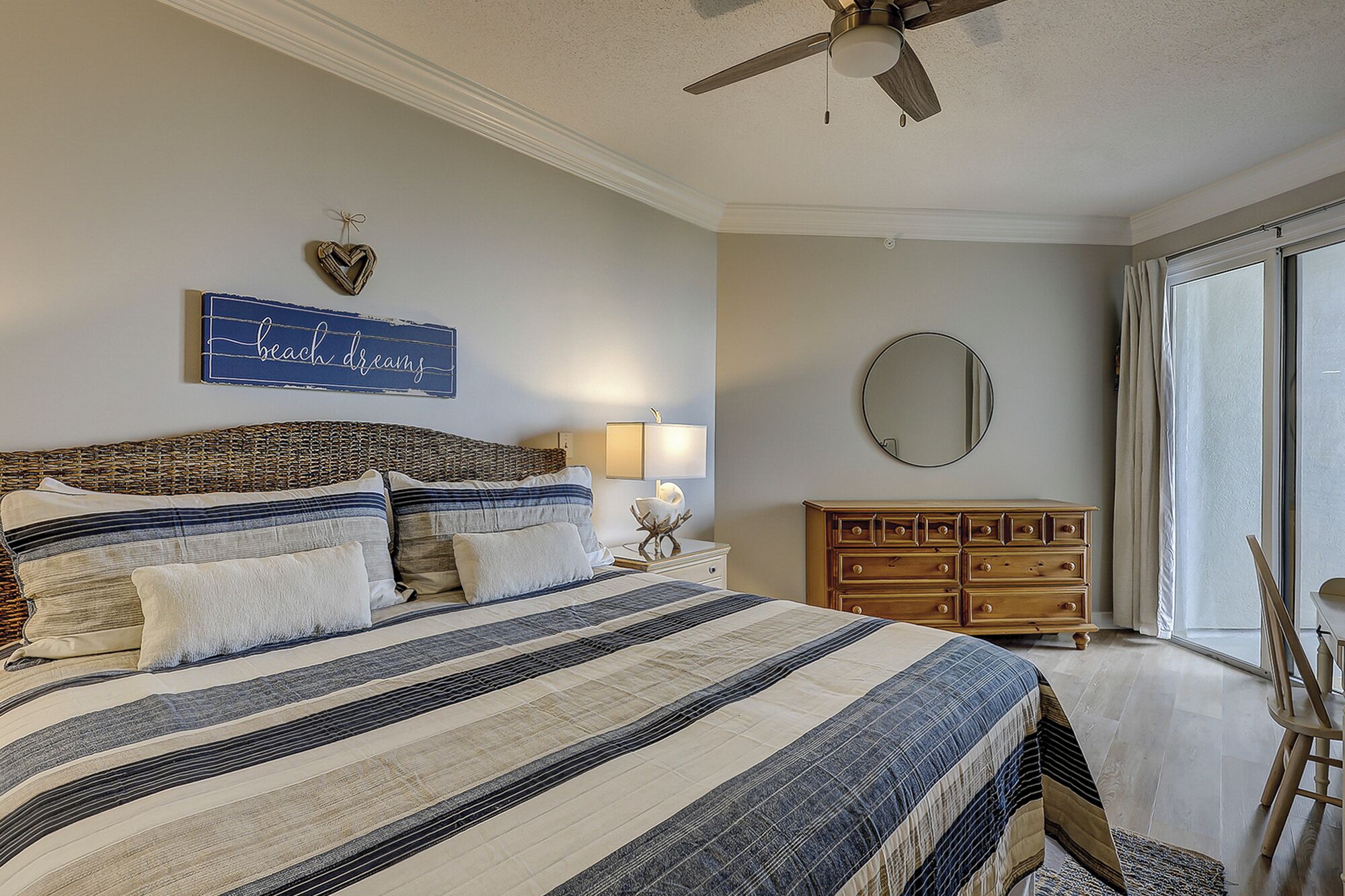 Un dormitorio con cama, cómoda, espejo y ventilador de techo.