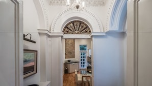 A hallway leading to a kitchen with a wooden floor, white walls, and a decorative ceiling. - The Patrick Kavanagh Suite - hiphipstay (Dublin)
