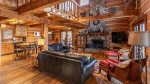 Un intérieur spacieux de chalet en bois avec une cheminée en pierre, un canapé en cuir et des meubles en osier.