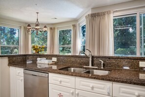 A kitchen with granite countertops, stainless steel sink, white cabinets, and a dishwasher. - Walk to Baytowne Wharf ~ Pool ~ Family Friendly (Miramar Beach)