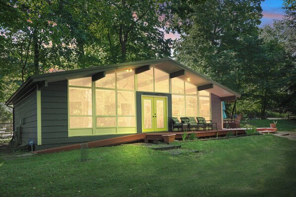 A small, single-story house with large windows and a porch. - Short Walk to Sandy Dunes | Lake Michigan | Adjacent to Mt. McSauba | Firepit (Charlevoix)