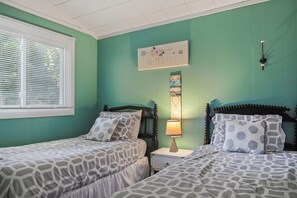 A bedroom with two beds, a nightstand, a wall clock, and a window with blinds. - Short Walk to Sandy Dunes | Lake Michigan | Adjacent to Mt. McSauba | Firepit (Charlevoix)
