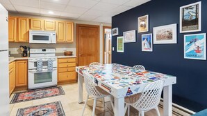 A compact kitchen with wooden cabinets, a microwave, an oven, and a dining table with a colorful placemat.