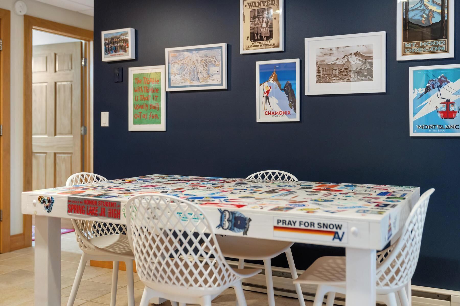 A dining area with a table covered in a colorful tablecloth, surrounded by white chairs.