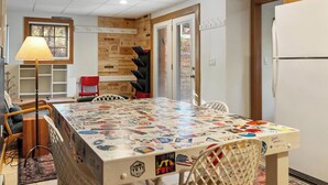 A kitchen with a table covered in stickers, a refrigerator, a lamp, and a red chair.
