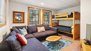 A compact living space with a sofa, a coffee table, bunk beds, and a framed picture on the wall.