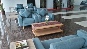 Un vestíbul modern amb sofàs blaus, una taula de centre de fusta i una revista damunt una taula auxiliar.