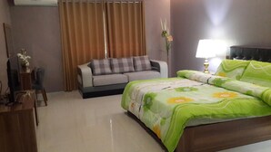 Habitació d'hotel amb un llit, un sofà, una taula de treball i una làmpada.