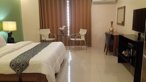 Habitació d'hotel amb un llit, dues cadires, una taula petita, una televisió i una estanteria.