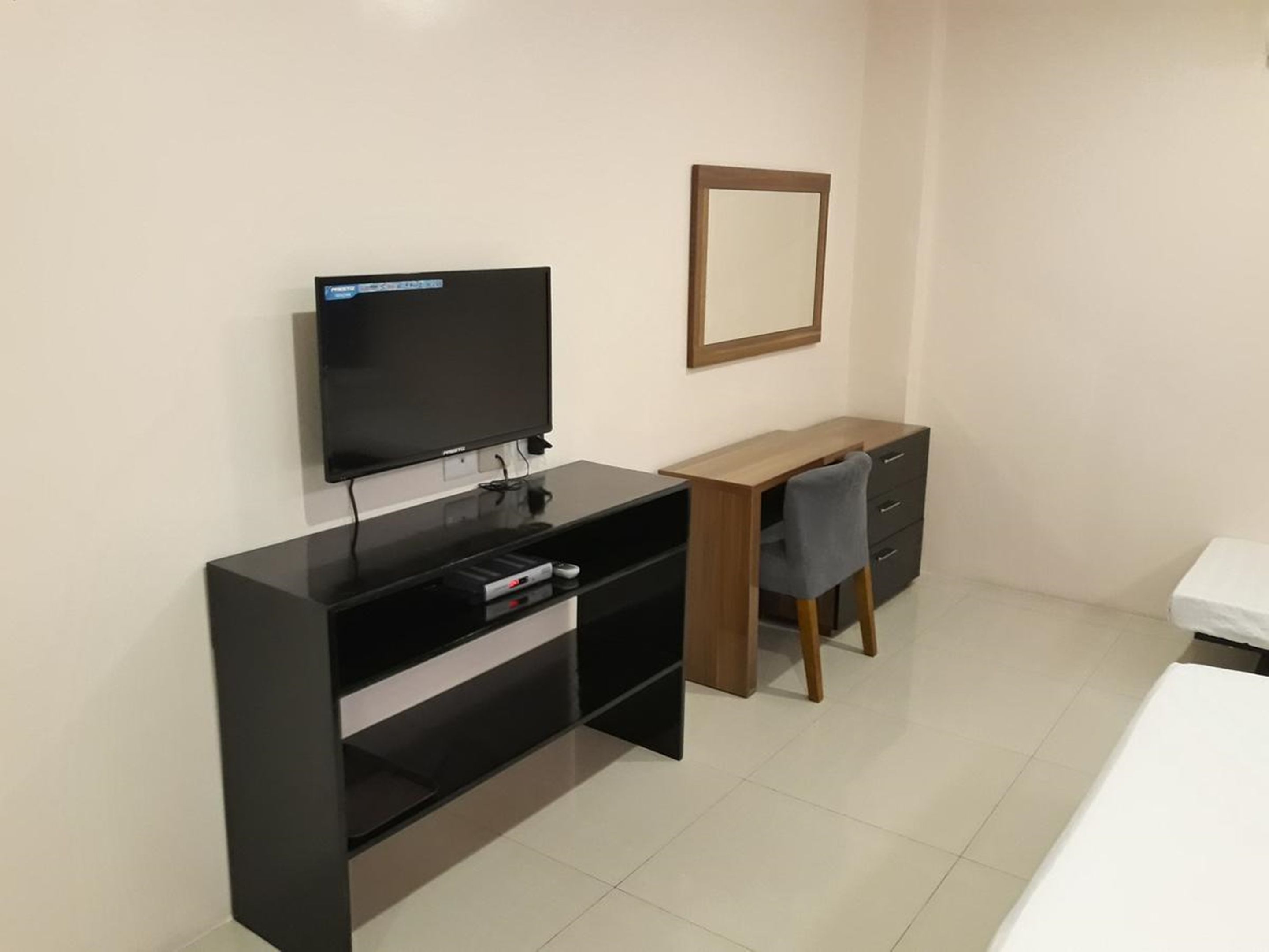 Una habitación de hotel moderna con televisión de pantalla plana, un escritorio de madera, una silla y una cama.