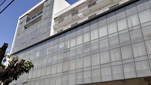 Un edifici comercial de diversos pisos amb façana de vidre, que inclou botigues com un supermercat i un banc.