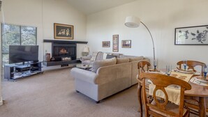 Una sala de estar con sofá, televisión, chimenea y comedor.