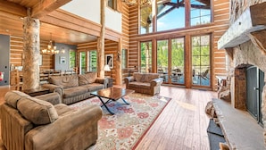 A spacious interior with wooden beams, a large chandelier, and a fireplace. - Bullshead By Tahoe Getaways - 4700SQ FT Luxury Riverfront Estate w Hot Tub (Olympic Valley)