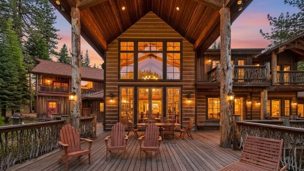 A log cabin with a deck, multiple windows, and a dining area. - Bullshead By Tahoe Getaways - 4700SQ FT Luxury Riverfront Estate w Hot Tub (Olympic Valley)