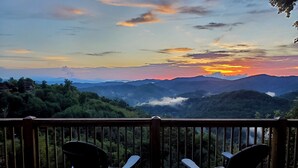 A wooden deck with two Adirondack chairs facing a mountainous landscape during sunset. - Ski-In Views & Hot Tub⛷️ Black Bear Lodge + 8 mins to Hatley Pointe (Mars Hill)