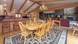 Un'ampia sala da pranzo con un tavolo e sedie in legno, un lampadario e un tappeto decorato.