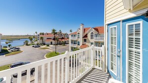 A residential building with a balcony, a parking lot, and a view of the water.