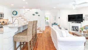 A spacious living area with a white sofa, a television, and a fireplace.