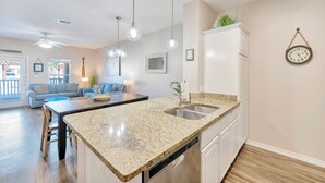 A modern kitchen with granite countertops, stainless steel appliances, and pendant lighting. - Coastal Retreat W/ Pool Views, Private Balconies and Spacious Living (Corpus Christi)