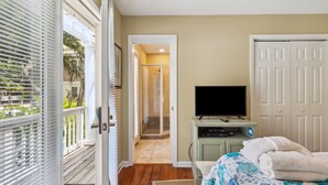 A bedroom with a bed, a television, a walk-in closet, and a door leading to a shower. - 15 Bittern Street | Cozy Home with Cottage & Pool | 4th Row | STR #028425 (Hilton Head Island)