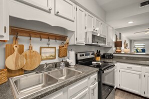 A modern kitchen with white cabinetry, stainless steel appliances, and a granite countertop.