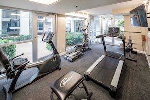 A gym with treadmills, elliptical machines, and a bench.