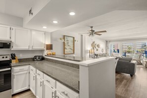 A modern kitchen with white cabinets, granite countertops, and a central island.