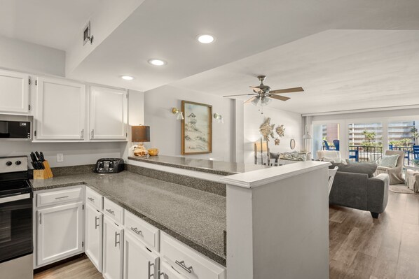 A modern kitchen with white cabinets, granite countertops, and a central island.