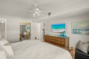 A bedroom with a bed, a dresser, a television, and artwork on the wall.