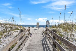 A wooden boardwalk leading to beach umbrellas and a lifeguard tower.