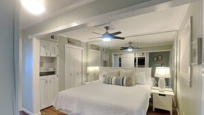A bedroom with a bed, two nightstands, a ceiling fan, and a walk-in closet.